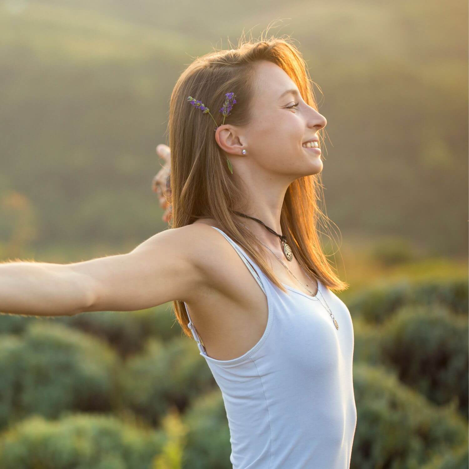 Mujer sonriendo al aire libre con los brazos abiertos, simbolizando frescura y bienestar.