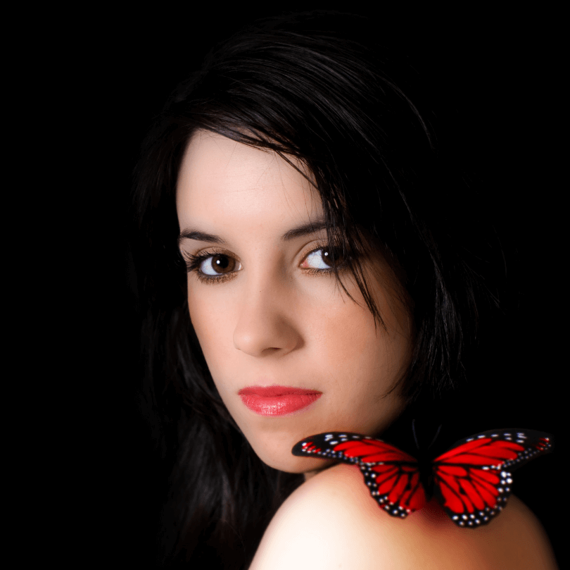 Mujer con labios rojos luciendo Aceite Esencial para Cuidado de Labios, con mariposa roja en su hombro.