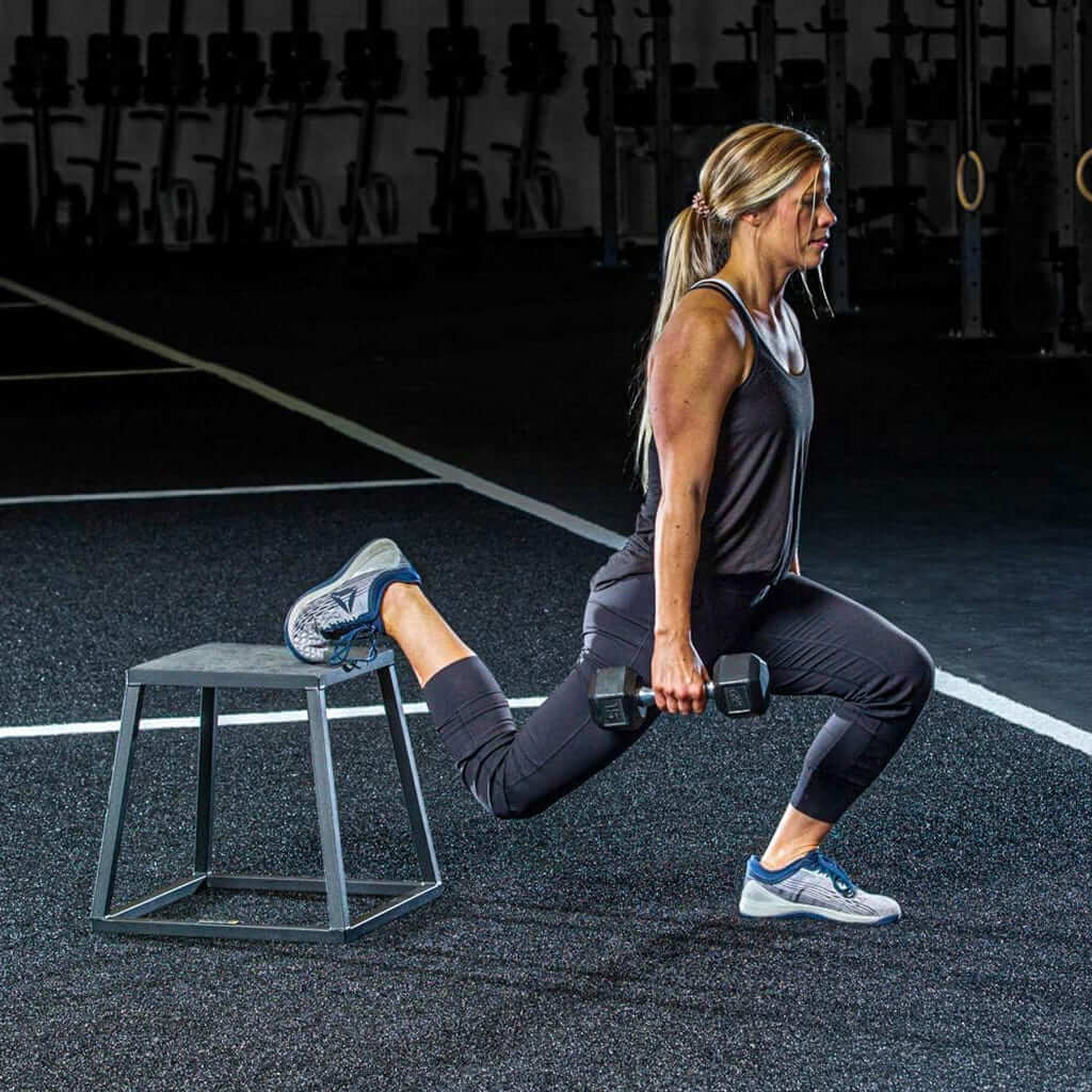 Mujer entrenando con pesas en un ejercicio de lunge usando EsencialLuz EleváBox como soporte.