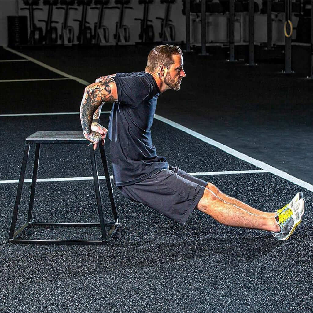 Hombre haciendo ejercicio de fondos en la EsencialLuz EleváBox en un gimnasio.